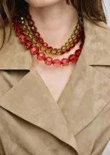 Collar corto de diseño multicapa, compuesto por cuentas facetadas de acrílico en tonos rojo, ámbar y verde.