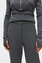 Pantalón sastrero de tiro alto con corte acampanado y pliegues frontales. Cuenta con cierre de botón y bolsillos decorativos.