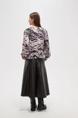 Blusa de manga larga con estampado animal print abstracto en tonos grisáceos y negros. Presenta cuello a la base y cierre con botón en la parte posterior.