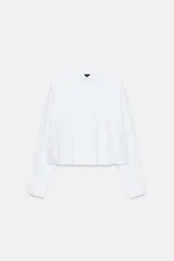 Camisa de popelín color blanco, con cuello solapa, manga larga y bajo abullonado con elástico interior. Cierre frontal con botones.