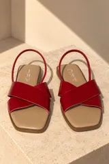 Sandalias planas de cuero con tiras cruzadas de pelo con estampado animal print tipo vaca en tonos marrón y blanco, plantilla beige y tira trasera fina de cuero marrón.