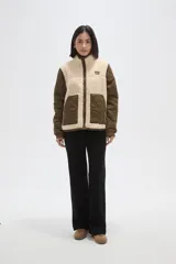 Campera de diseño híbrido que combina paneles de corderito sintético en color crema con mangas y bolsillos de tela técnica acolchada en color verde militar. Presenta cierre frontal completo, cuello alto y un pequeño parche decorativo en el pecho.