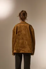 Chaqueta tipo biker de gamuza sintética color tostado, con cuello solapa, cierre frontal y diseño holgado.