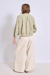 Cazadora azul de manga larga con puños elásticos, cuello redondo sin solapas y cierre frontal con botones grandes de color claro.