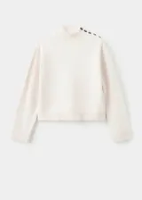 Jersey de punto medio color blanco, con diseño recto, cuello perkins y manga larga. Presenta un detalle de botones decorativos en el hombro.