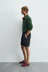 Polo de manga larga con cuello solapa y cierre frontal de botones. Presenta un tejido jacquard texturizado con rayas horizontales en tonos de verde.