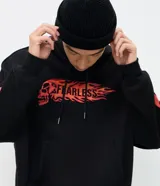 Buzo con capucha negro de corte oversized, con bolsillo canguro y cordones ajustables. Presenta un estampado frontal con una calavera y la palabra 'FEARLESS' envuelta en llamas naranjas y rojas, diseño que se repite en las mangas.