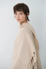 Ruana de tejido de punto en color negro, con diseño de cuello alto y terminaciones con flecos en los bordes.