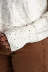 Sweater de tejido de punto color blanco roto con efecto tweed o confeti, caracterizado por pequeñas motas de colores. Presenta cuello redondo y un calce holgado (oversize).