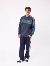 Sweater de cuello redondo marca Rusty, con diseño de bloques de color en azul marino y verde, con detalles de líneas blancas. Presenta el logo de la marca bordado en el pecho.