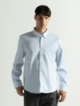 Camisa celeste y blanca a cuadros con cuello abotonado, manga larga y bolsillo en el pecho.