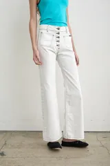Jeans de denim blanco de tiro alto, corte recto y amplios bolsillos frontales aplicados. Cuenta con cierre frontal abotonado con múltiples botones metálicos a la vista y pespuntes en contraste.
