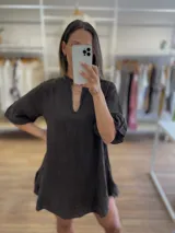 Vestido corto de lino 100% color celeste claro, con escote en V y cuello mao. Tiene mangas cortas y un ruedo con volados.