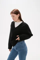 Sweater de punto color blanco, con cuello en V, manga larga y diseño holgado.