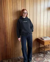 Canguro negro de corte oversize, con capucha ajustable mediante cordones y bolsillo frontal tipo canguro. Presenta un estampado frontal con la palabra 'KABOA' en tipografía gótica de color verde claro.