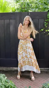 Vestido largo de seda estampada con flores amarillas sobre fondo blanco, corte halter.