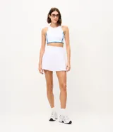 Top deportivo femenino confeccionado en microfibra, de color blanco con vivos en azul, escote redondo, copa y breteles anchos.