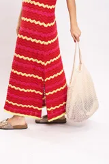 Vestido largo de tejido de punto con diseño de rayas en zigzag de colores rojo, fucsia y amarillo. Presenta cuello redondo y diseño sin mangas.
