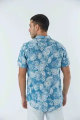 Camisa de manga corta con estampado botánico de hojas en tonos azul y blanco. Presenta cuello clásico, cierre frontal abotonado y corte slim.