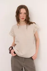 Blusa de lino color beige con mangas cortas y detalles de crochet en las mangas, de cuello redondo y corte holgado.