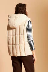 Chaleco puffer crudo matelaseado con capucha y cierre frontal de cremallera.