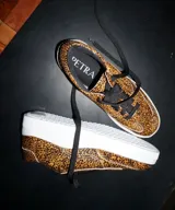 Zapatillas bajas con estampado animal print de leopardo, cordones negros y suela blanca.