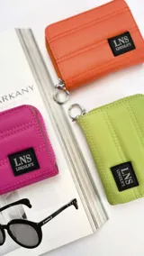 Billetera corta de diseño capitoneado con cierre perimetral y tapa. Cuenta con compartimentos internos para tarjetas y billetes, e incluye una correa de mano desmontable.