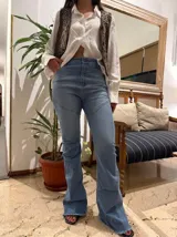 Jean de tiro alto con corte acampanado y diseño de costuras diagonales en las piernas. Presenta un acabado deshilachado en el ruedo.