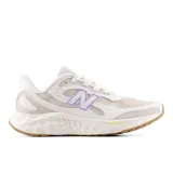 Championes deportivos New Balance modelo Arishi V4, con tecnología de amortiguación Fresh Foam en la entresuela. Presentan un diseño en tonos blanco y beige con detalles en lila en el logo lateral y la lengüeta, y suela de goma color caramelo.