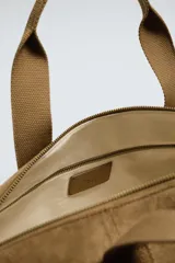 Bolso de viaje de estilo minimalista con acabado liso. Cuenta con un compartimento principal con cierre de cremallera, un bolsillo interior con cierre, un bolsillo frontal plano, asas de mano y un asa de hombro ajustable y extraíble.