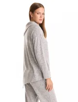 Buzo de calce suelto confeccionado en tejido suave melange color gris. Presenta cuello volcado con botones decorativos en el hombro izquierdo, mangas largas con hombros caídos y ruedo asimétrico con terminación en punta.