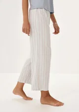 Pijama compuesto por una remera de manga corta color celeste con estampa frontal y un pantalón largo de corte recto con estampado de rayas verticales en tonos neutros.