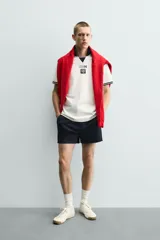 Polo de corte relajado confeccionado en piqué de algodón color blanco. Presenta cuello solapa en color negro con abertura frontal, mangas cortas con ribetes a contraste y estampado conmemorativo USA 94 FIFA World Cup.