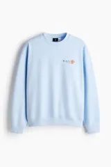 Buzo celeste de corte holgado con hombros caídos y cuello redondo. Presenta un pequeño estampado en el pecho con la inscripción "Matisse" y un detalle gráfico en color naranja.