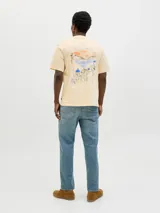 Remera color crema de algodón con cuello redondo, manga corta y estampado en la espalda con un paisaje costero.