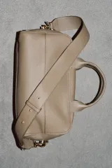 Bolso alargado tipo bowling color verde oliva, confeccionado en cuero con doble asa de mano y asa bandolera extraíble. Incluye bolsillo interior con cremallera y cierre principal con cremallera.