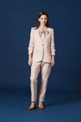 Saco de vestir para mujer con silueta estructurada, cierre frontal de un botón, solapas clásicas y bolsillos laterales con solapa. Presenta mangas con detalle fruncido y un diseño elegante de textura suave.
