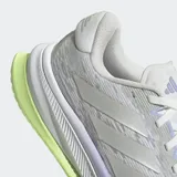 Championes de running Adidas Supernova Comfortglide para mujer, diseñados con un exterior de malla textil y sintética en color gris claro. Incorporan la tecnología Dreamstrike en la mediasuela para una amortiguación superior, detalles reflectantes para mayor visibilidad y una suela en contraste de color verde lima con acentos violetas.