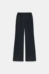 Pantalón de felpa color negro, de tiro medio y corte ancho. Presenta cintura elástica, bolsillos laterales ocultos y aplicación de brillos en toda la parte frontal.