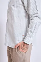 Camisa de corte regular con diseño de rayas verticales finas en tonos claros, cuello clásico y mangas largas con puños abotonados.