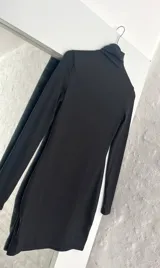 Vestido corto negro de mangas largas y cuello alto.