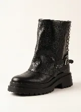 Bota corta de cuero negro con diseño de polaina superpuesta, detalle de tachas metálicas en el lateral y correa con hebilla ajustable. Cuenta con suela track de goma y taco cuadrado.