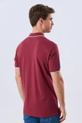 Remera polo de piqué azul marino, con cuello y puños de mangas cortas con ribete blanco en contraste, cierre frontal de dos botones y pequeño logo bordado en el pecho.