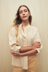 Camisa blanca de manga 3/4 confeccionada en algodón liviano con diseño calado y detalles de encaje en el frente. Cuello con volados.