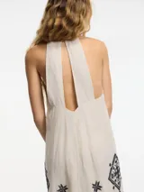 Vestido largo color beige con breteles finos y bordado de motivos geométricos en negro.