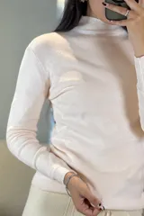 Buzo de tejido de punto fino en color verde, con cuello medio y mangas largas, de corte ajustado al cuerpo.