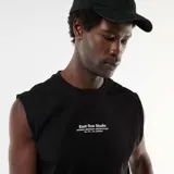 Musculosa negra de algodón con cuello redondo y diseño holgado, con pequeño estampado frontal con texto en blanco.