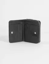 Billetera plegable color bordó con textura efecto cuero, cierre perimetral y placa metálica con logo en el frente.