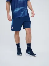 Short de entrenamiento Umbro del Club Nacional de Football, modelo Trace para hombre. Color azul marino con franjas laterales en celeste y escudo del club en la pierna derecha.