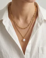 Collar doble de acero dorado, compuesto por una cadena de eslabones rectangulares y una cadena fina con dije de perla de río natural.